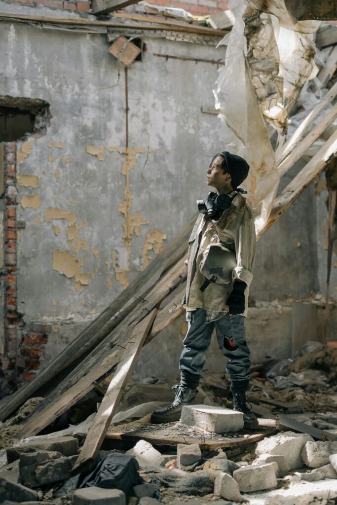 A young man stands amidst the ruins of a dilapidated building, embodying a post-apocalyptic feel.